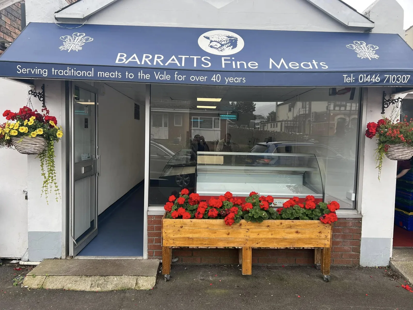 The Barratts Fine Meats shopfront in Rhoose, with hanging baskets and a new serve-over counter visible through the window