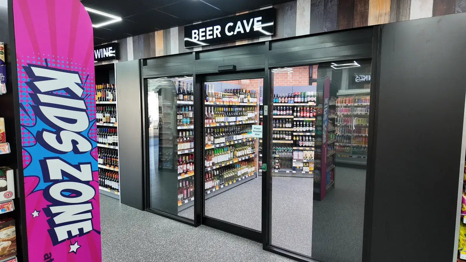 The Beer Cave — branded glass-door cold room entrance with brick-effect surround